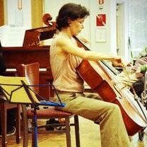 A man playing the cello in front of other musicians.